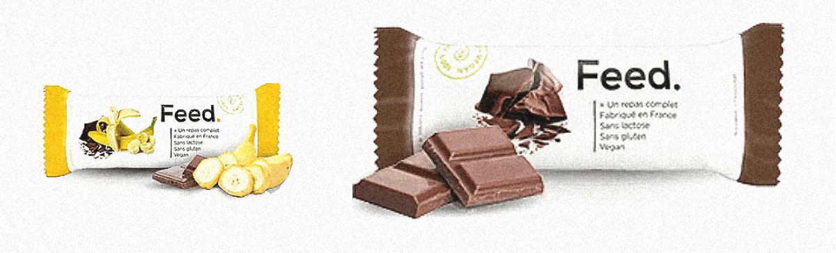 deux barres feed emballées dont une chocolat banane et une chocolat avec des morceaux de chocolat devant.