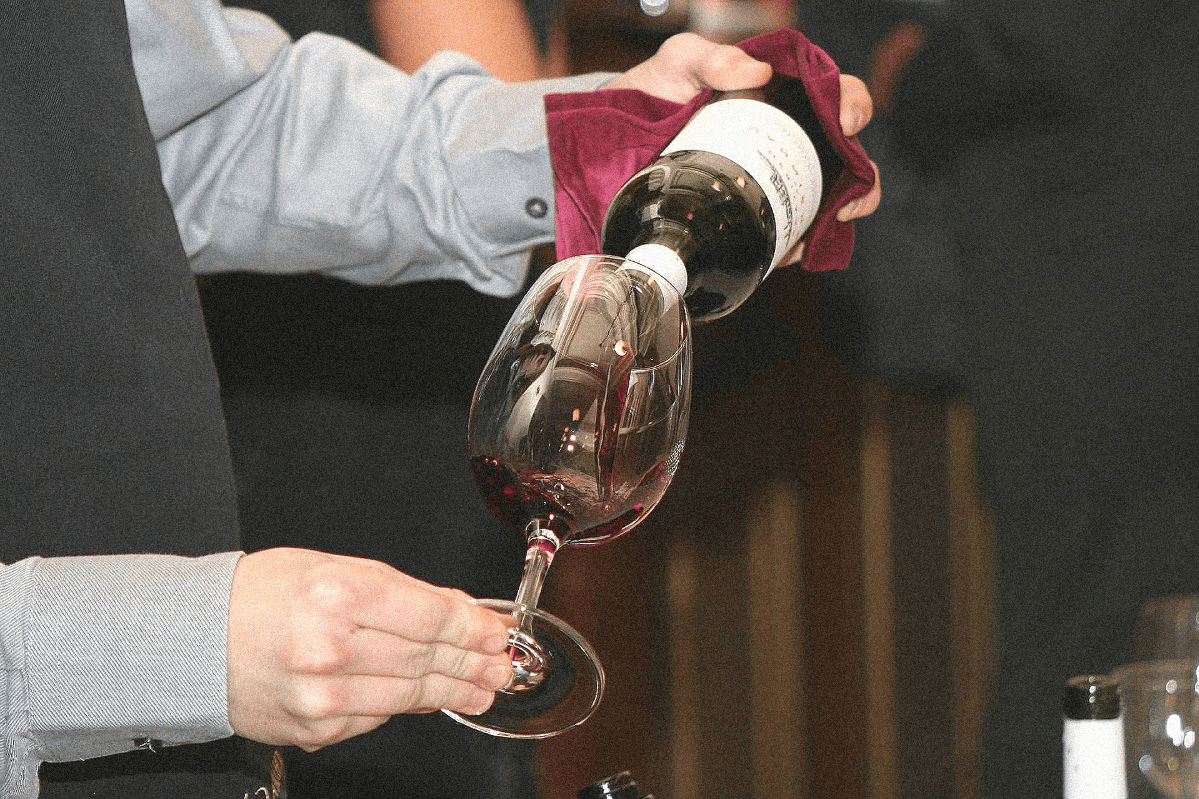 deux bras servant du vin dans un verre